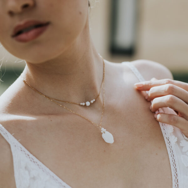 Collier de mariage pendant avec une feuille en porcelaine et des perles de Swarovski porté par un mariée.