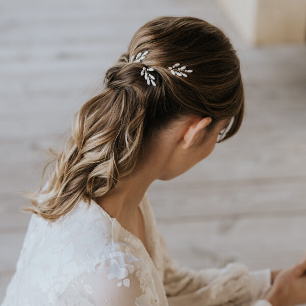 Accessoires cheveux de mariage en nacre et perles de Swarovski, portés par un mariée. Ces bijoux de mariage sont composés d'épingles à chignon.
