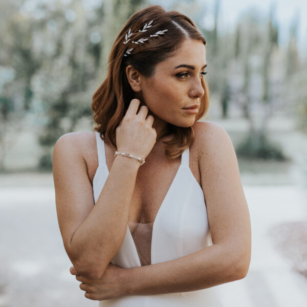 Mariée portant ses bijoux de mariage, un bracelet perlé et strassé et des epingles à chignon dans sa coiffure.