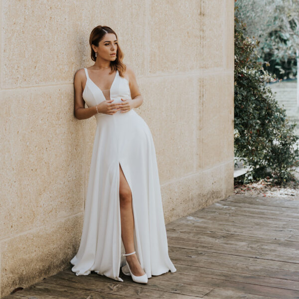 Jeune mariée portant ses bijoux de mariage. La parure se compose d'un collier simple et délicat avec de perles et du cristal de Swarovksi, des boucles d'oreilles avec gouttes et un bracelet alternant perles et cristal.