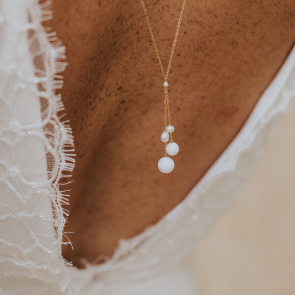 Pendentif en perles d'eau douce et porcelaine d'un collier de dos pour une mariée portant une robe dos nu.