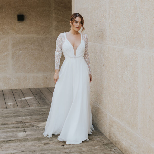 Mariée portant des bijoux de mariage élégants et minimalistes en perles d'eau douc et porcelaine. Elle porte un collier ras de cou sur une fine chaîne, un bracelet et des boucles d'oreilles pendantes.