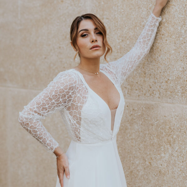 Mariée portant des bijoux de mariage élégants et minimalistes en perles d'eau douc et porcelaine. Elle porte un collier ras de cou sur une fine chaîne, un bracelet et des boucles d'oreilles pendantes.